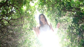 Girl in woods with sun shining on her
