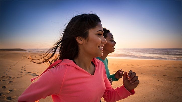 two young women running on a beach