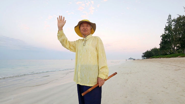 Ilchi Lee waving on a Hawaiian beach